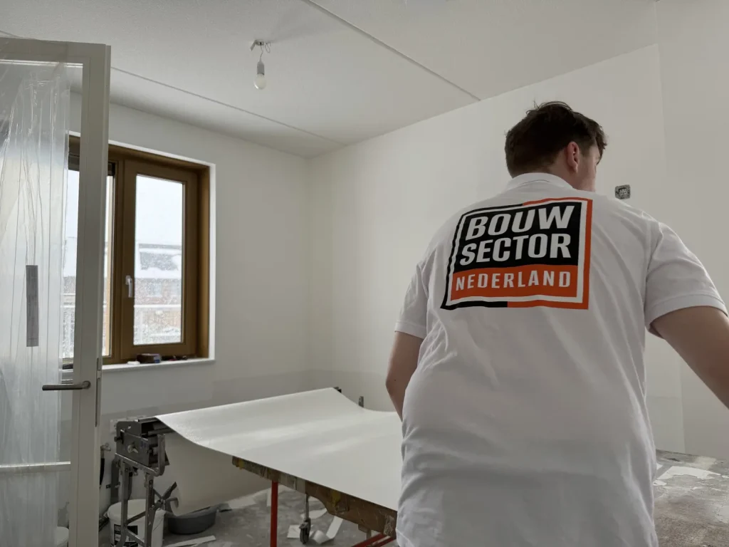 Behanger van Bouwsector Nederland rolt een baan vlies uit op de plaktafel