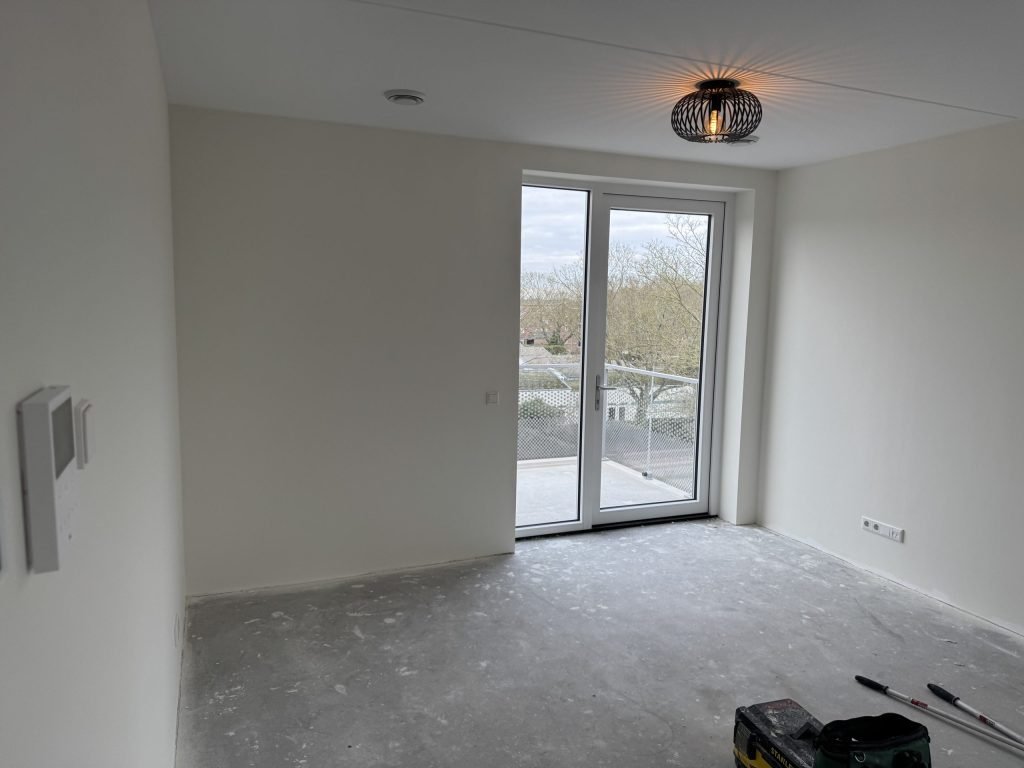 Net opgeleverd appartement met witte wanden en een deur naar het balkon